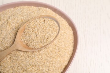 Oat bran in bowl and spoon on light table, closeup