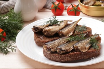 Delicious sandwiches with sprats, dill and tomatoes on white wooden table, closeup