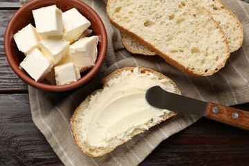 Fresh bread with butter and knife on wooden table, flat lay