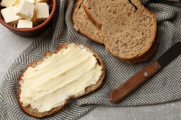 Fresh bread with butter and knife on grey table, flat lay