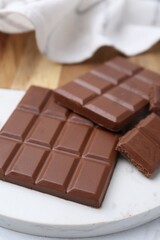 Pieces of delicious milk chocolate on white table, closeup