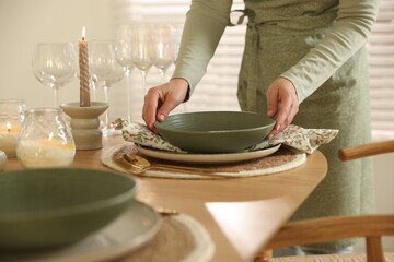 Woman setting table for dinner at home, closeup