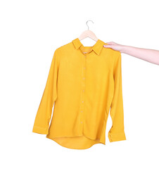 Woman holding hanger with yellow shirt on white background, closeup