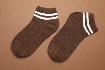 Pair of soft socks on light brown background, top view