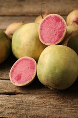 Whole and cut fresh turnips on wooden table, closeup