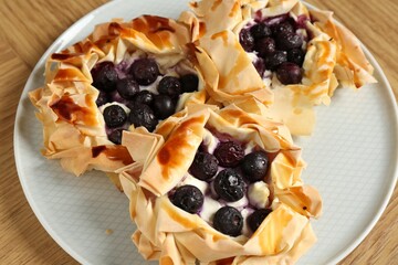 Delicious puff pastries with blueberries on wooden table, closeup