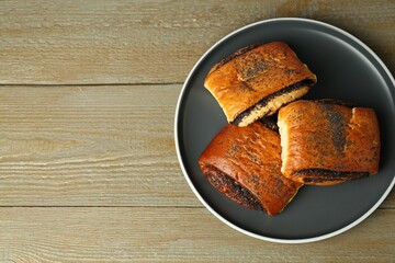 Tasty buns with poppy seeds on wooden table, top view. Space for text