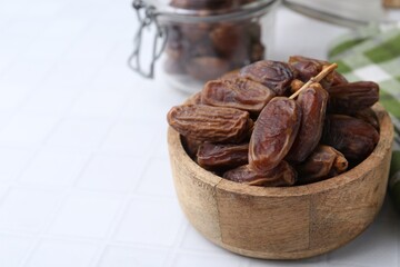 Tasty dried dates on white tiled table, closeup. Space for text