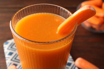 Fresh carrot juice in glass on brown table, closeup