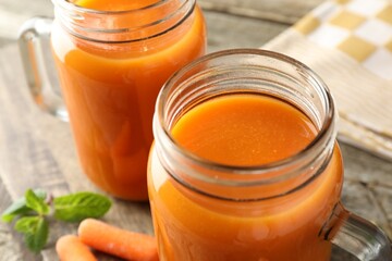Fresh carrot juice in mason jars on table, closeup