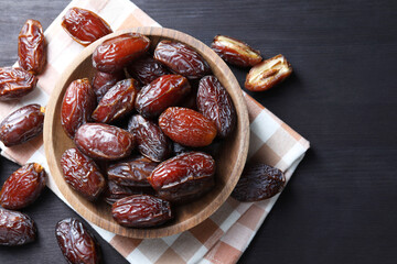 Tasty dried dates on black table, top view