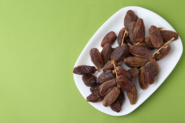 Tasty dried dates on green background, top view. Space for text