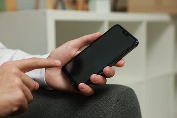 Man using smartphone with blank screen indoors, closeup