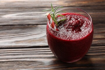 Fresh beetroot smoothie with rosemary in glass on wooden table, closeup. Space for text
