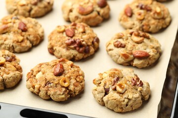 Tasty cookies with nuts in baking tray, closeup