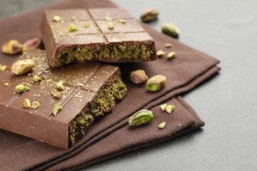 Fototapeta premium Pieces of tasty Dubai chocolate with pistachios and knafeh on grey table, closeup