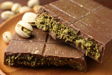 Pieces of tasty Dubai chocolate bar with pistachios and knafeh on table, closeup