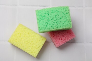 Soft sponges on white tiled table, flat lay