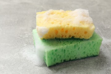 Sponges and foam on light grey table, closeup