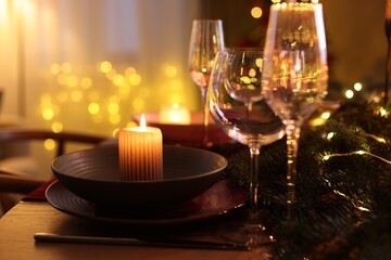 Festive table setting in room decorated for Christmas, closeup. Bokeh effect