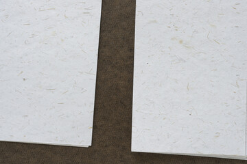 Fototapeta premium two piles of textured paper with natural elements on brown board