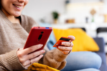 Close up female hands holding credit card and smart phone, paying online, making virtual purchase or shopping online