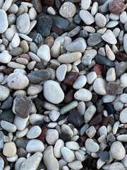 Pebble sea beach close-up. Smooth round pebbles texture background. Gray and white sea stones. 