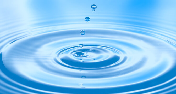 Water drops on pastel blue bright background. Colorful circles water surface with rings and ripples from water drops splash. Ecology or SPA concept.