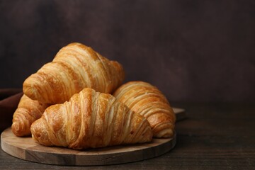 Tasty fresh croissants on wooden table, closeup. Space for text