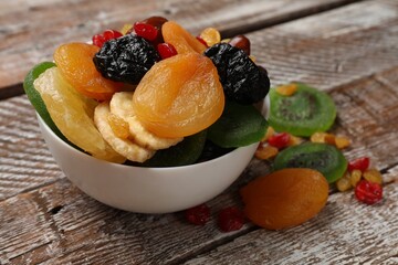 Mix of different dried fruits in bowl on wooden table, closeup