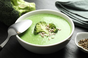 Delicious broccoli cream soup served on black table, closeup
