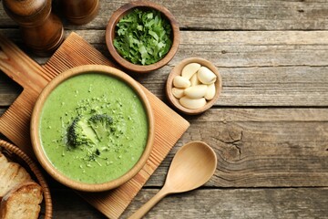 Delicious broccoli cream soup served on wooden table, flat lay. Space for text
