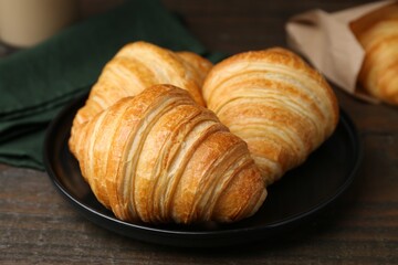 Tasty fresh croissants on wooden table, closeup. Puff pastry