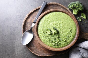 Delicious broccoli cream soup served on grey table, flat lay