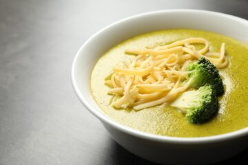 Delicious broccoli cream soup in bowl on gray table, closeup. Space for text