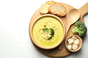 Delicious broccoli cream soup served on white wooden table, flat lay. Space for text