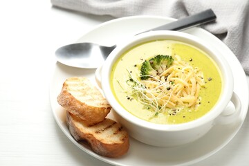 Delicious broccoli cream soup served on white wooden table, closeup