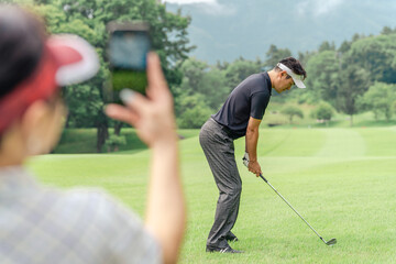 ゴルフ場でスマホを使って動画を撮ってスイングの確認をするゴルファー

