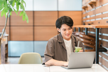 カフェ・家でノートパソコンを使う若い男性（テレワーク・リモートワーク）

