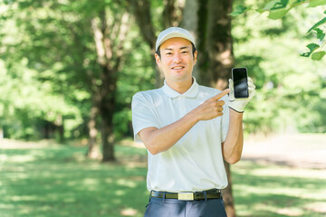 ゴルフ場でスマホを使う男性ゴルファー（アプリ・スコア・スコア管理・コース戦略・コースマップ）
