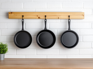Three Black Frying Pans on Wooden Rack Against White Brick Wall