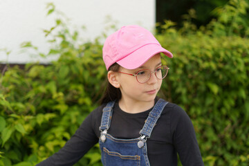 Little cheerful girl in pink baseball cap and glasses in summer outdoors. Concept of children's travel, fun, health