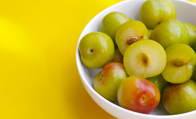 Fresh green plum fruit on yellow background.