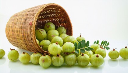 Fresh Indian gooseberries spill from a woven basket onto a white background.