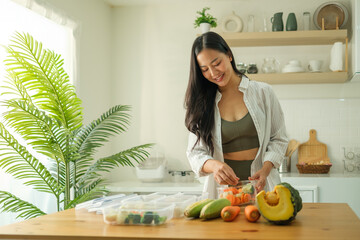 Fitness young woman preparing meal containers with fresh vegetables in kitchen. Health and nutrition concept.