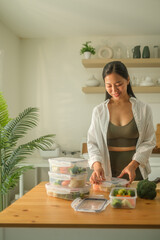 Young smiling sportswoman preparing containers with mixed vegetables for freezer.