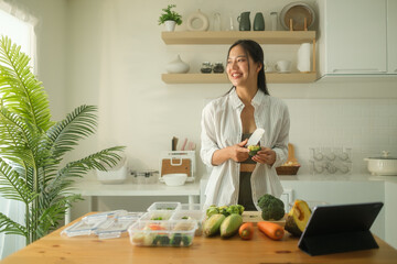 Sporty young woman preparing containers of healthy food in kitchen. Meal preparation, healthy...