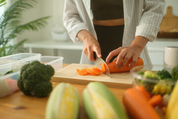 Close up shot of a woman assembling nutritious vegetables into clear plastic containers on a kitchen counter, ready for meal preparation