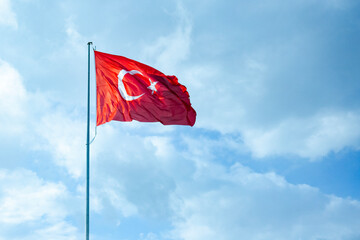 Turkish flag fluttering in the wind against a blue sky with clouds, travel to Turkey, Turkish vacation