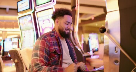 A young man joyfully celebrates his significant victory while enthusiastically playing a slot machine in a lively casino, capturing the pure excitement and thrill of a stunning jackpot win